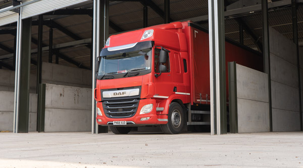 A large red lorry sits in a yard.